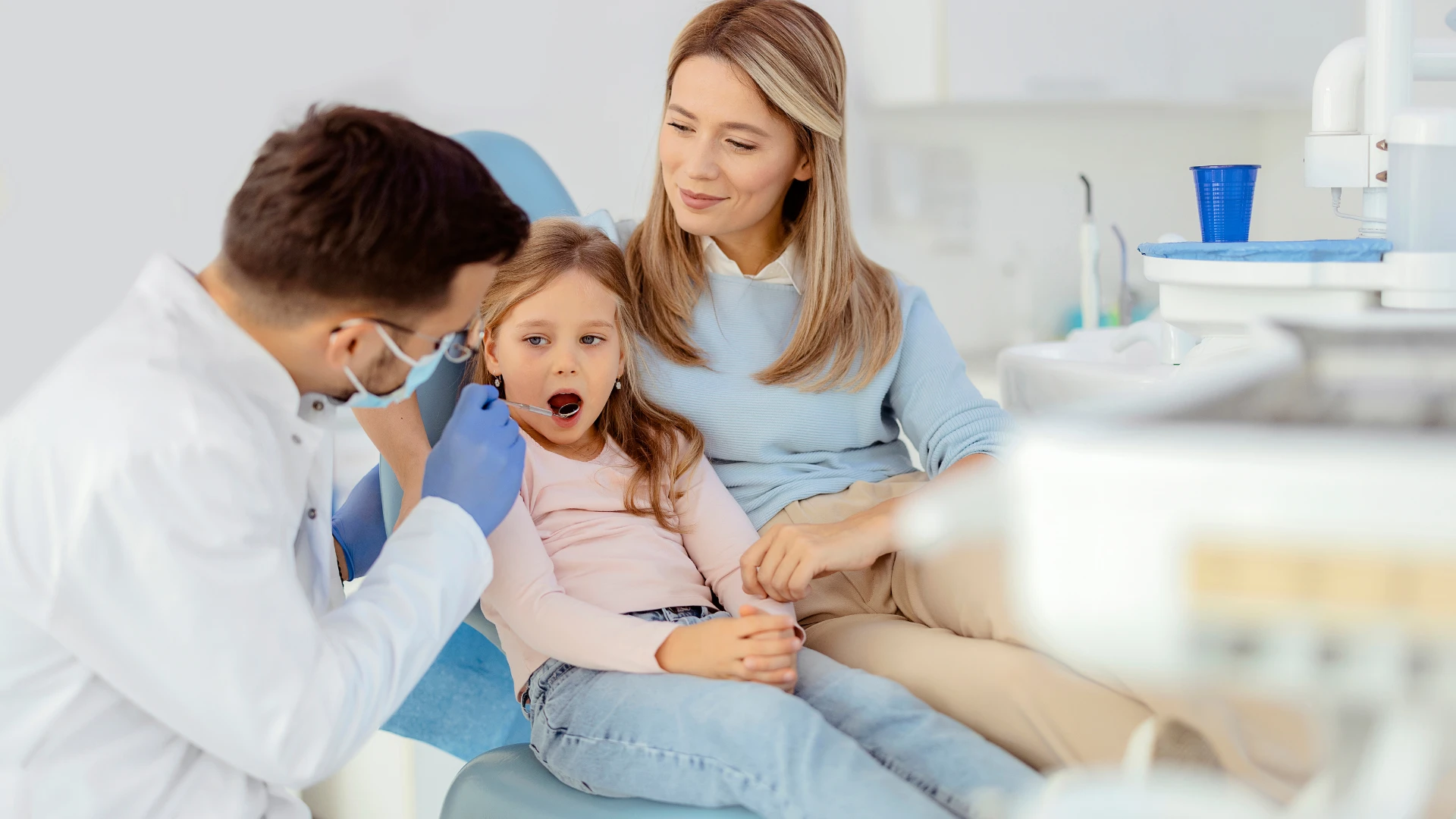 Family dentist treating young child and parent in a warm, friendly dental office